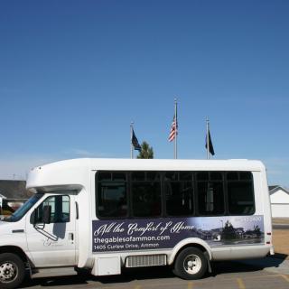 A white shuttle bus parked outdoors with flags flying in the background.