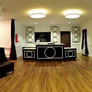 A stylish modern lobby featuring a unique black and white reception desk, complemented by wooden flooring and contemporary lighting.