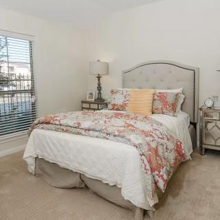 A cozy and elegantly decorated bedroom with a comfortable bed, stylish lamps, and a large window.