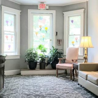 A cozy living room with large windows, plants, and comfortable seating.