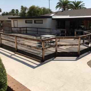 A sunny backyard view featuring a house with a wooden ramp and deck.