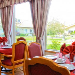 A cozy dining area with elegantly set tables and a view of the garden outside.
