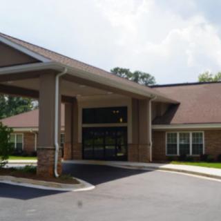 A building entrance with a covered driveway and landscaped surroundings.