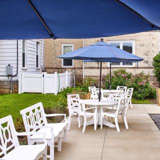 Outdoor patio area with white furniture and blue umbrellas.