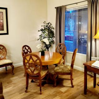 A cozy living room featuring a wooden dining set, soft lighting, and decorative plants.