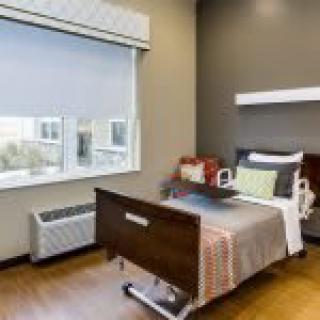 A clean and well-lit hospital room with a single bed and large window.