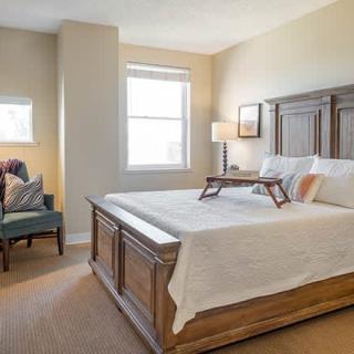 A cozy bedroom with a large wooden bed, a bedside lamp, and comfortable seating.