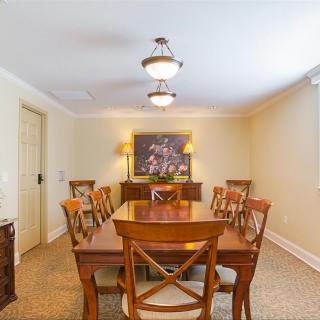 A well-lit dining room with a wooden table and chairs, adorned with artwork on the wall.