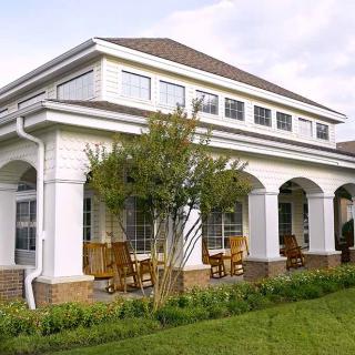 A two-story suburban house with a spacious porch and well-maintained lawn.