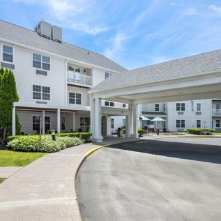 A white hotel building with a covered entrance and driveway under a clear blue sky.