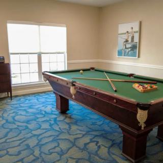 A billiards room with a pool table, cue sticks, and balls arranged for a game.