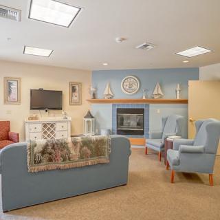 A cozy living room with blue and beige tones, featuring a fireplace, television, and nautical decor.