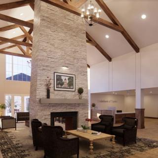 A spacious living room featuring a tall stone fireplace, wooden beams, and comfortable seating.