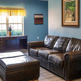 A cozy living room with a leather sofa and a desk by the window.