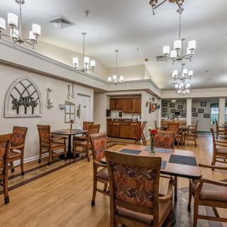 A well-lit dining room with wooden tables and chairs, featuring elegant lighting and decor.