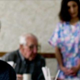 A caregiver attending to an elderly person in a nursing home setting.
