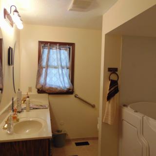 A cozy bathroom with a single sink, mirror, and window with curtains.