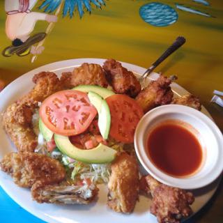 A delicious plate of fried chicken served with fresh vegetables and dipping sauce.