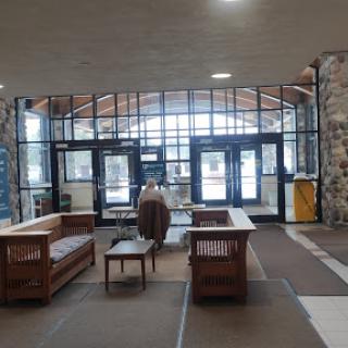 A spacious lobby featuring wooden seating and large glass windows.