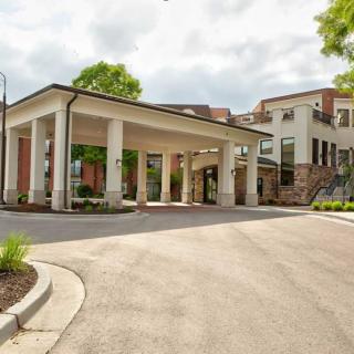 A modern building with a covered entrance and a circular driveway.