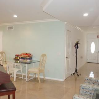A cozy living and dining area with a glass table, chairs, and a coat rack near the entrance.