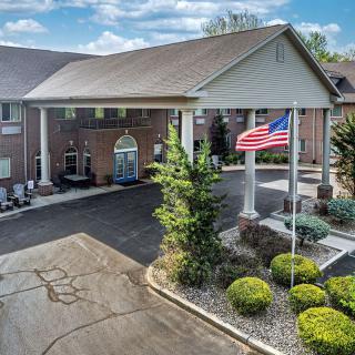 A building with an entrance, an American flag, and landscaped surroundings on a cloudy day.