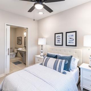 A modern bedroom with elegant decor, featuring a neatly made bed, stylish lamps, and framed wall art.