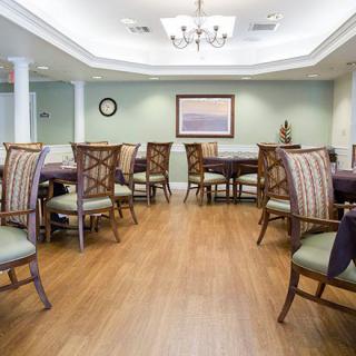 A spacious dining room with elegant chairs and tables, featuring a chandelier and hardwood flooring.