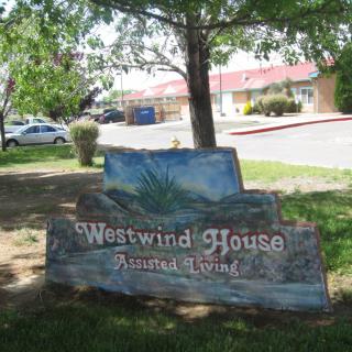 A sign for Westwind House, Assisted Living, located outdoors near a building and trees.