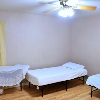 A minimalist bedroom with two single beds and a ceiling fan.