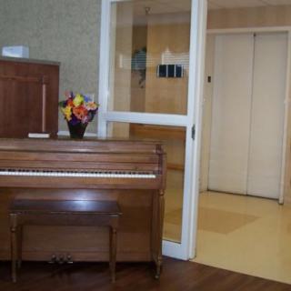 A cozy room with a wooden piano and a bouquet of flowers on top.