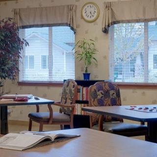 A quiet room with tables, chairs, and a clock on the wall.