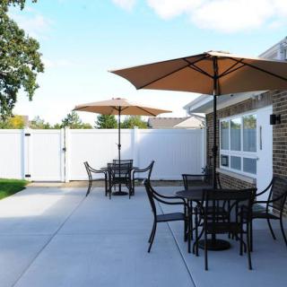 A sunny backyard patio with tables and chairs under large umbrellas.
