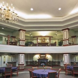 A spacious lobby with a chandelier, balconies, and dining tables.