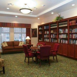 A cozy library with bookshelves, a seating area, and warm lighting.