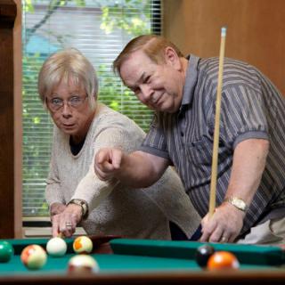 Two seniors enjoying a game of billiards together.