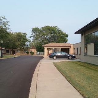A quiet residential street with a car parked near the entrance of a building.