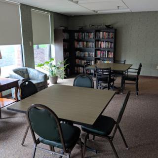 A quiet study area featuring multiple tables and chairs surrounded by bookshelves.