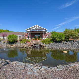 A scenic landscape with a pond in front of a building under a clear blue sky.