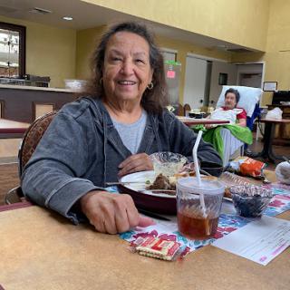 A cheerful woman enjoying a meal and drink in a cozy dining area.