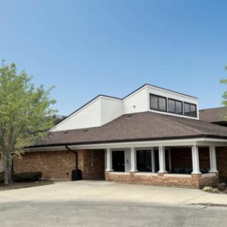 A suburban building with a modern architectural design, surrounded by trees on a clear day.