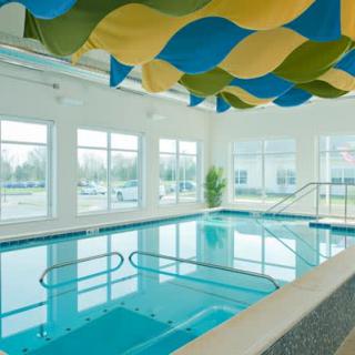 A bright indoor swimming pool with modern decor and large glass windows.