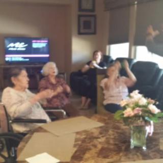 A group of people enjoying a celebration in a living room with flowers on the table.