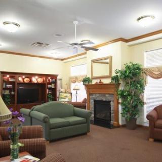 A cozy living room featuring comfortable furniture, a television, and a fireplace surrounded by elegant decor and plants.