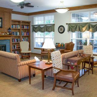 A cozy living room with comfortable seating, bookshelves, and large windows.
