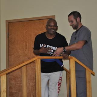 A healthcare professional assists a patient in walking during rehabilitation, showcasing support and progress.