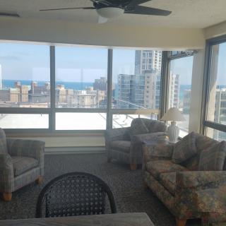 A cozy living room with large windows offering a cityscape and ocean view.