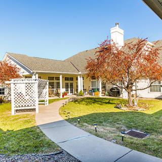 A charming house with a landscaped backyard featuring autumn-colored trees and a patio.