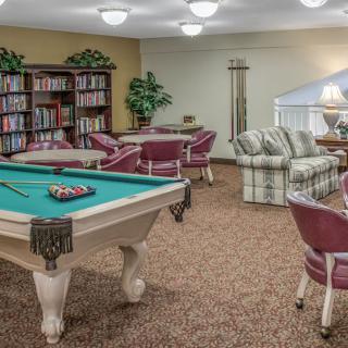 A cozy recreational room featuring a pool table, bookshelves, and comfortable seating areas.