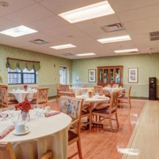 A well-lit dining room with several decorated tables and chairs, featuring tasteful decor and large windows.